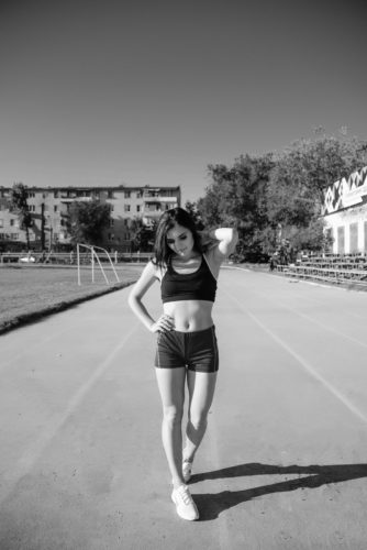 Young woman athlete on stadium sporty lifestyle standing on track posing looking camera smiling joyful